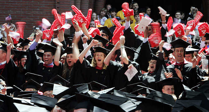 Students from the Harvard Business School cheer as they receive their degrees in Cambridge, Massachusetts.
