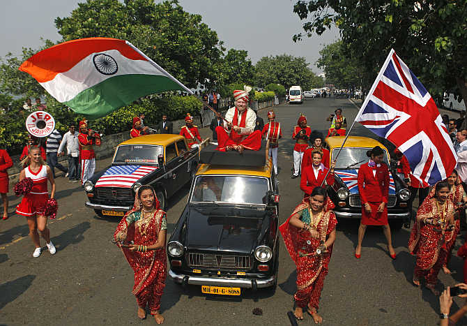 Virgin Group founder Richard Branson waves an Indian national flag while sitting atop a taxi in Mumbai.