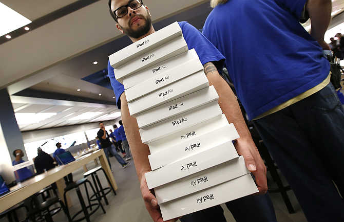 An employee carries a stack of iPad Air tablets inside the Apple Store on New York's Fifth Avenue.