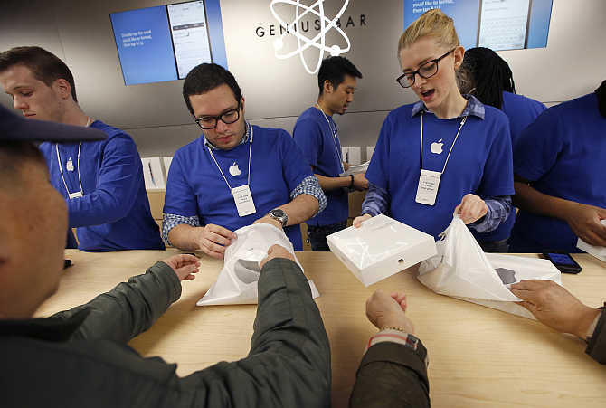 Employees help customers buying iPad Air tablets inside the Apple Store on New York's Fifth Avenue.