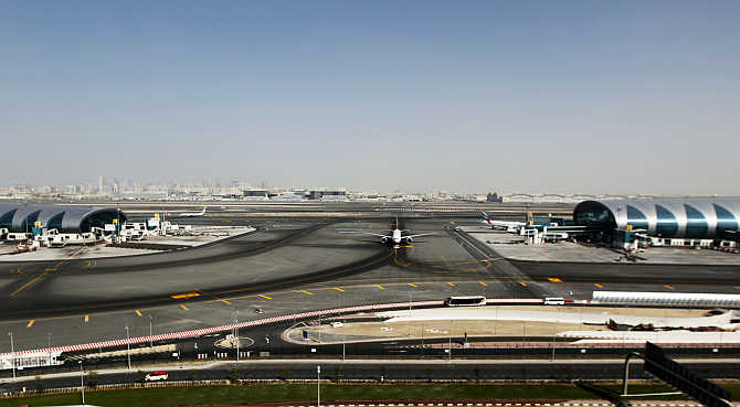 A plane passes in between the Emirates Airlines terminal, left, and a terminal dedicated for A380 aircraft, right, at the concourse in Dubai International Airport.