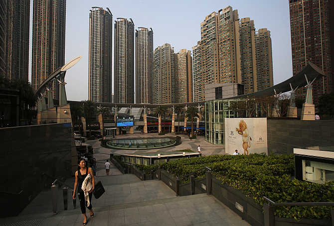 A woman walks up the stairs as luxurious high rise residential buildings are seen at Hong Kong's West Kowloon district.