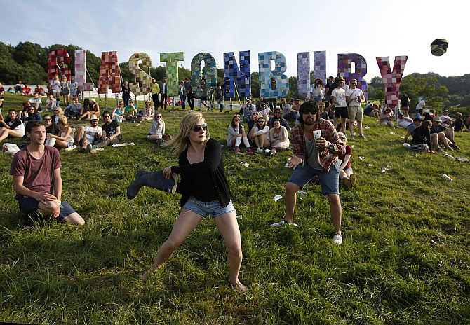 Festival goers play rounders with a wellington boot and a beer can at the Glastonbury music festival at Worthy Farm in Somerset, United Kingdom.