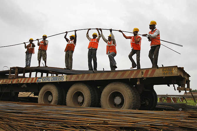 Workers unload iron rods from a truck at a construction site on the outskirts of Ahmedabad.