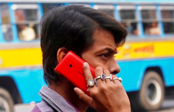 A man uses a mobile phone to make a call on a street in Kolkata.