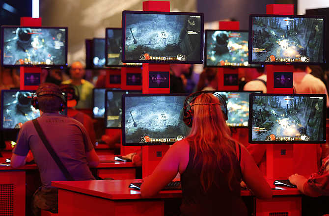 Visitors play Diablo at the Blizzard exhibition stand during the Gamescom 2013 fair in Cologne, Germany.