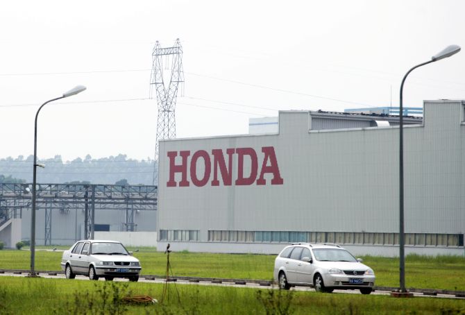 Cars drive past Honda Auto Parts Manufacturing Co. Ltd. plant in Foshan.