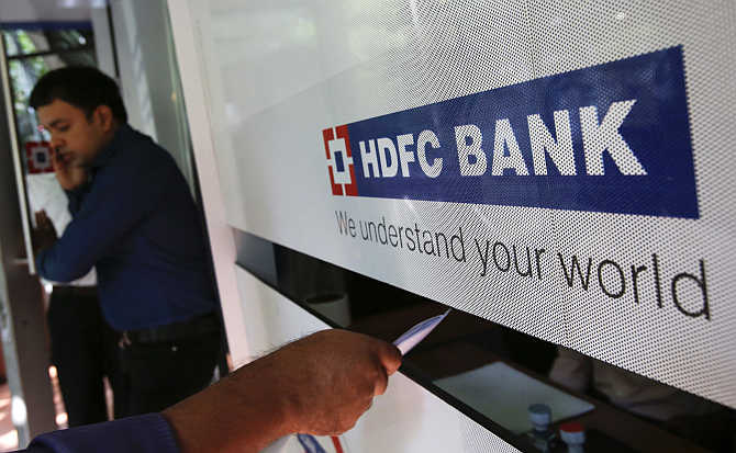A customer walks out of a HDFC Bank branch as another deposits a cheque at a counter in Mumbai.