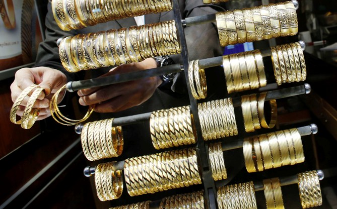A goldsmith arranges gold bangles at a jewellery shop.