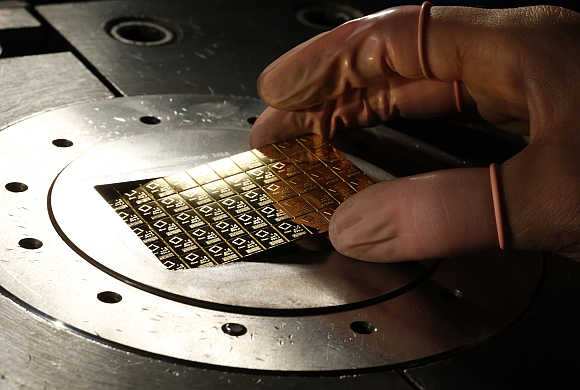 An employee takes a gold Combibar out of a press machine in Balerna, Switzerland.