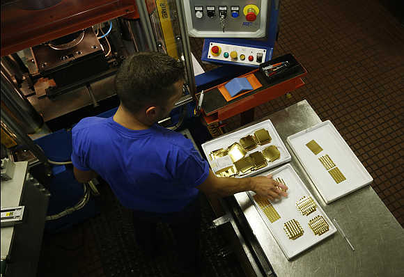 An employee places a gold Combibar into a press machine in Balerna, Switzerland.