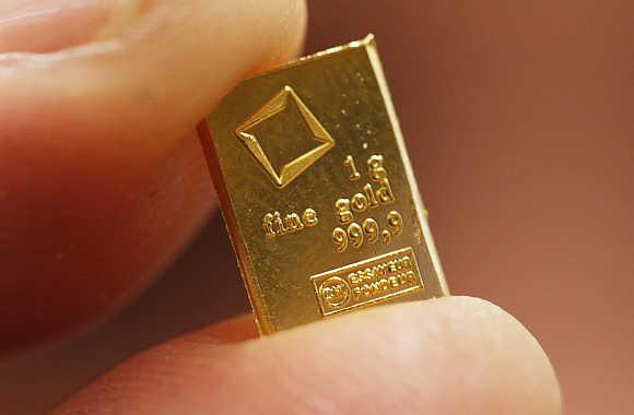 An employee shows a one gram piece of a gold Combibar in Balerna, Switzerland.