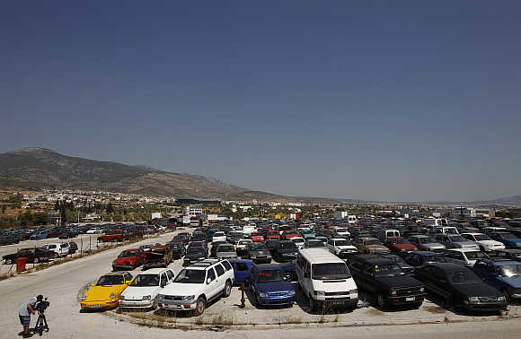 A cameraman films confiscated cars in a yard of Oddy in Athens.