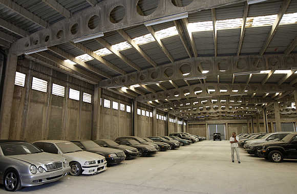 A man walks by confiscated luxury cars inside a warehouse of Oddy in Athens.
