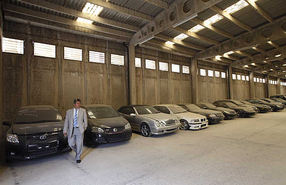 Oddy's Manager Dimitris Kouvaris walks by confiscated luxury cars in the warehouse in Athens.