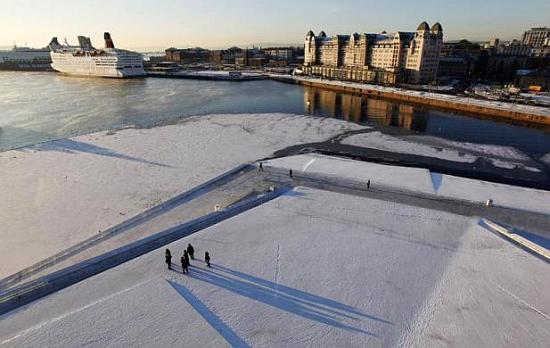 Pedestrians walk by the harbour during winter in Oslo.