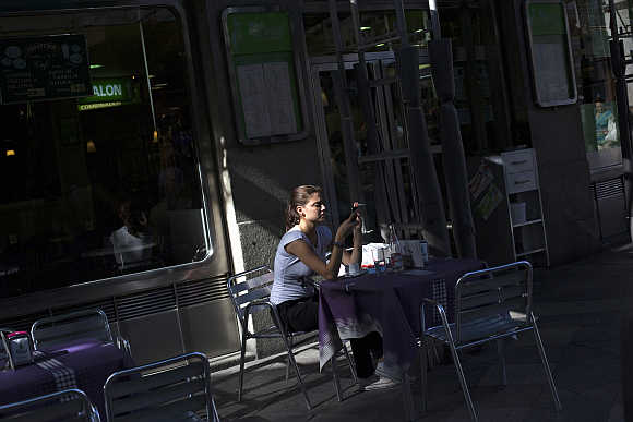 A woman checks her mobile phone at a shopping district in Madrid, Spain.