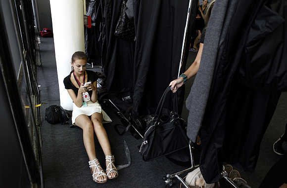 A model uses her mobile phone backstage before Osklen's Winter collection during Sao Paulo Fashion Week.