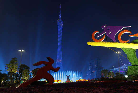Sports sculptures are pictured in front of the Canton TV Tower, also known as Guangzhou TV Tower, lit by coloured lights in Guangzhou, in Guangdong province, China.