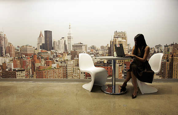 A Google employee works on a laptop in front of a mural of the New York City skyline, at the New York City company office.
