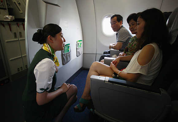 A crew member of Spring Airlines talks with travellers onboard an Airbus A320 aircraft at Hongqiao airport in Shanghai.