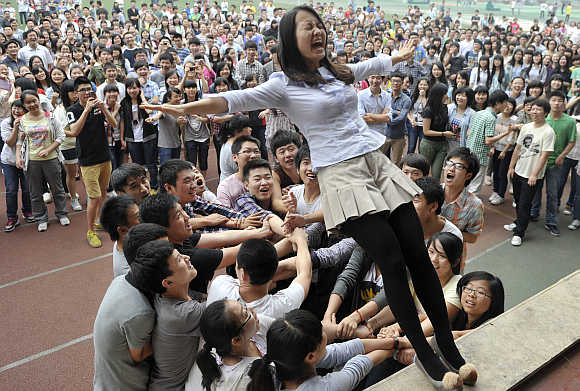 A teacher falls backwards from a higher ground as students get ready to catch her during a pressure releasing exercise ahead of the National College Entrance Exams at a high school in Chongqing municipality.