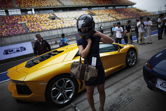 A woman puts on a helmet as she stands next to a Lamborghini in Shanghai.