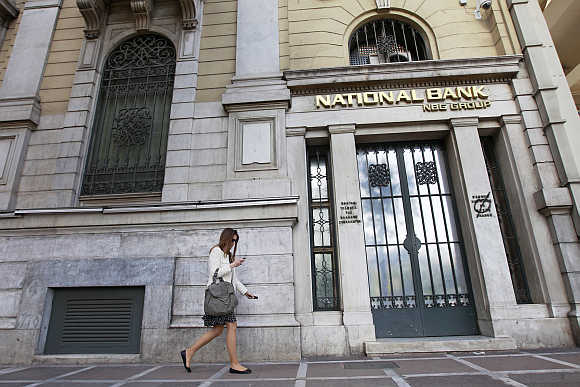 A woman walks outside a National Bank of Greece branch in central Athens.
