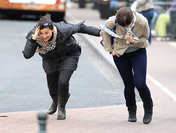 Women help each other to cross a square during strong wind in central Brussels.