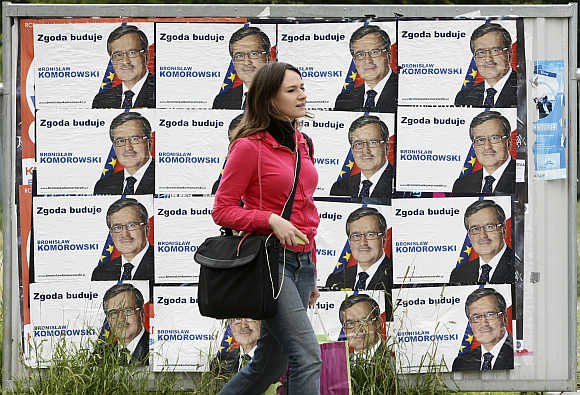 A woman passes posters of a politician in the centre of Warsaw.