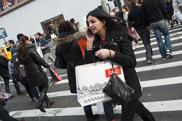 People carry shopping bags as they make their way in Herald Square in New York City.