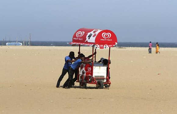 Workers move an ice-cream cart from the Marina beach in Chennai.