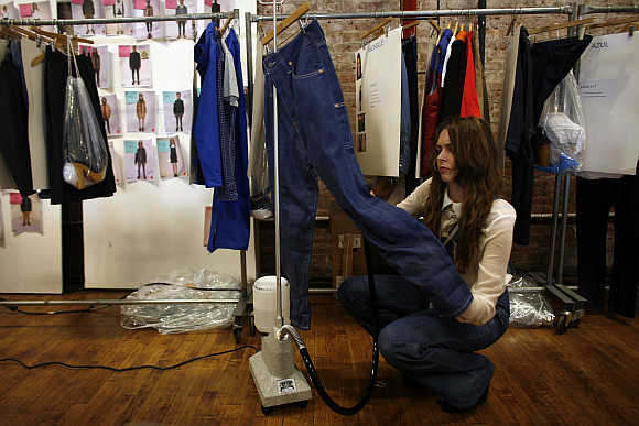 A woman steams a pair of jeans backstage during a fashion show New York.