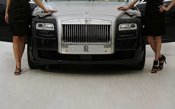 Models pose beside a Rolls Royce Ghost in Hong Kong.