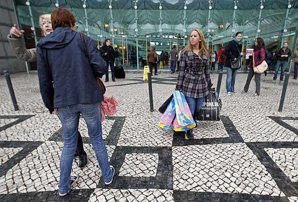 People walk outside the entrance of a shopping mall in Lisbon.