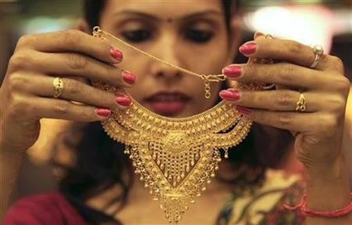 A salesgirl shows a gold necklace to customers at a jewellery showroom in Chandigarh.
