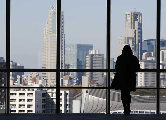 A woman looks at highrise buildings in Tokyo, Japan.