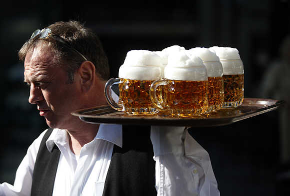 A waiter serves beer in a garden restaurant in Vienna.
