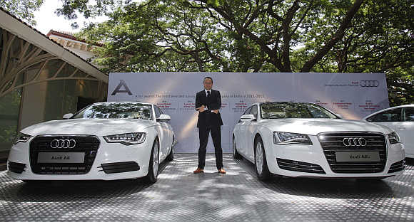 Michael Perschke, head of Audi India, poses between an Audi A6 and an Audi A8L in Mumbai.