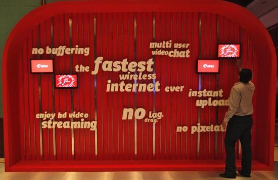 A man touches a screen on a Bharti Airtel ad billboard during the launch ceremony for 4G services in Kolkata.