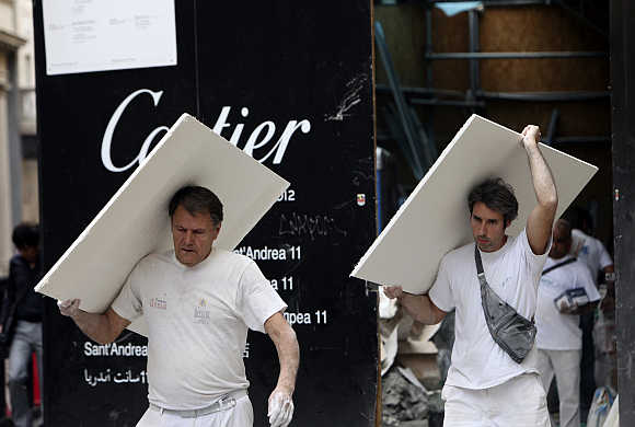 Workers carry materials outside a construction site in downtown Milan.
