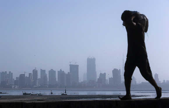 A labourer carries a sack of cement against a backdrop of the central Mumbai financial district.