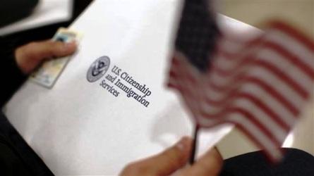 A man holds a US flag while receiving his proof of US citizenship during a ceremony in San Francisco, California