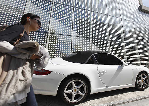 A woman walks past a Porsche on the Garosugil or the Tree-Lined Street in the Gangnam area of Seoul.