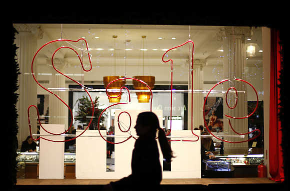 A woman walks past a sale sign in a shop window of Oxford Street in London.