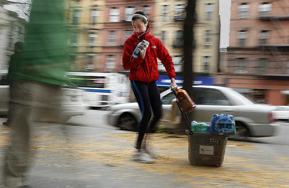 A woman drags a basket full of bottled water down 7th Ave in New York.