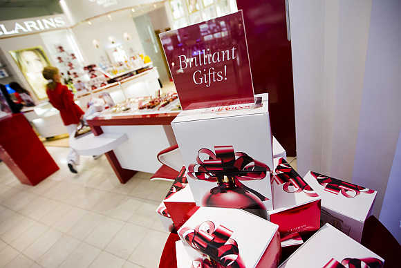 A woman walks behind a Christmas display that reads Brilliant Gifts at a shopping mall in Toronto, Canada.