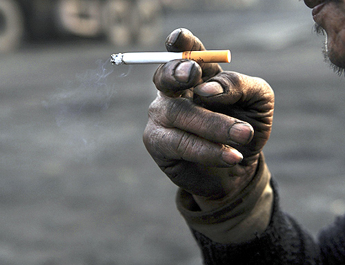 A worker smokes a cigarette during a break at a coal freight yard.