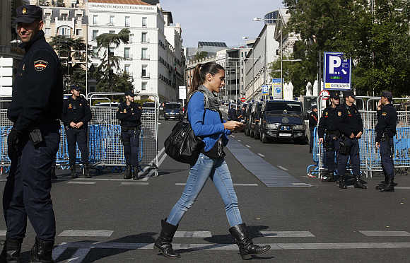 A woman walks past police deployed around Spain's parliament ahead of a demonstration in Madrid.