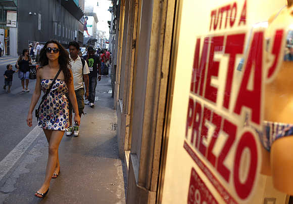 A woman walks in front of a shop window in downtown Rome.